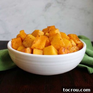 Feast Worthy Thanksgiving Sides 23 A pristine serving bowl generously filled with perfectly roasted butternut squash cubes, caramelized to a golden hue and ready to be enjoyed as a wholesome side dish.