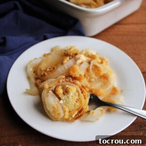 Feast Worthy Thanksgiving Sides 30 A delectable serving of cheesy onion casserole on a plate, featuring tender, softened onion rings beneath a savory blanket of cheese and a crispy, buttery cracker topping, ready to be enjoyed.