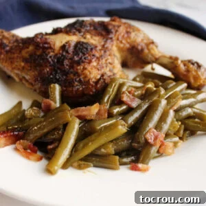 Feast Worthy Thanksgiving Sides 31 A hearty plate featuring a perfectly grilled chicken breast served alongside a generous portion of smothered green beans, rich with bacon and a sweet and sour sauce.