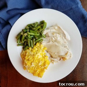 Feast Worthy Thanksgiving Sides 5 A dinner plate featuring a hearty serving of roasted turkey, rich gravy, vibrant green beans, and a generous portion of creamy scalloped corn casserole.