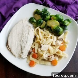 Feast Worthy Thanksgiving Sides 6 A dinner plate featuring tender homemade chicken and egg noodles with carrots, served alongside roasted Brussels sprouts and perfectly sliced turkey breast.