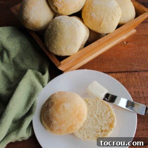 Feast Worthy Thanksgiving Sides 10 A beautifully cut 3-Day dinner roll, revealing its soft, airy interior, placed beside a basket filled with more warm, golden-brown rolls, inviting indulgence.