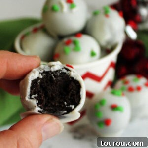 31 Sweet Homemade Treats 19 A hand holds a white chocolate-coated Oreo truffle, revealing its smooth center of Oreo and condensed milk mixture.