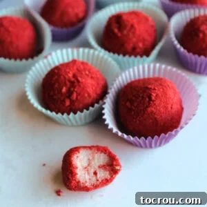 31 Sweet Homemade Treats 31 A strawberry brigadeiro with a bite missing, revealing its creamy pink interior and the coating of red freeze-dried strawberry powder.