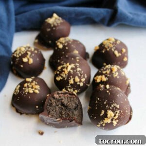 31 Sweet Homemade Treats 6 Peanut butter Oreo balls dipped in chocolate and topped with chopped peanuts, with one cut in half revealing its rich chocolatey center.