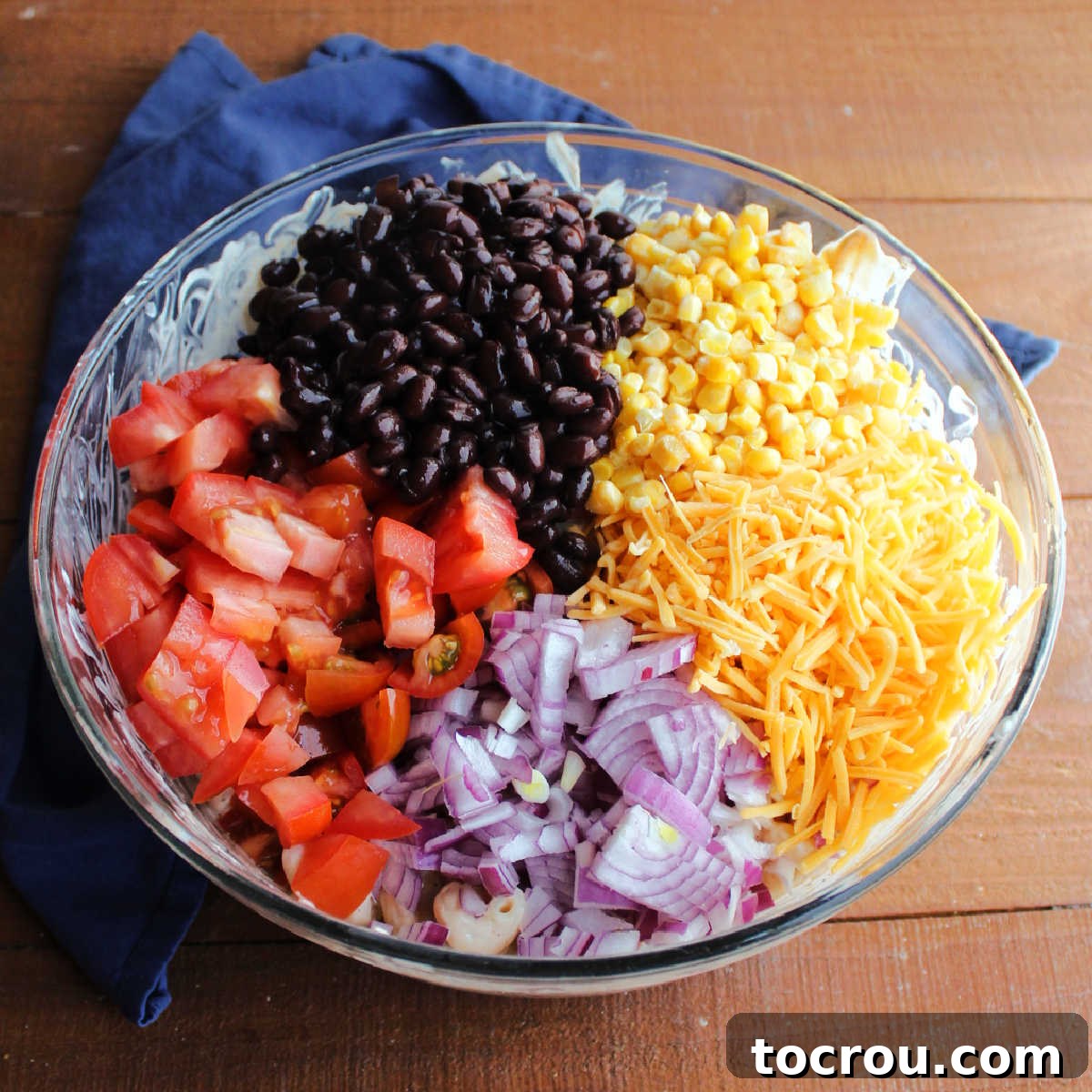 Vibrant vegetables for BBQ Ranch Pasta Salad Tomatoes, red onion, cheese, corn and black beans ready to be stirred into the bbq ranch macaroni salad.