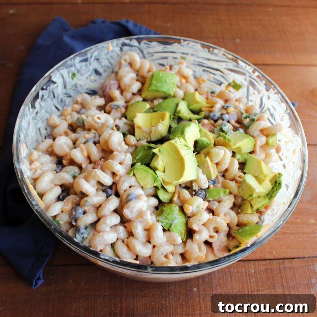 Adding avocado to BBQ Ranch Pasta Salad Stirring diced avocado into chilled bbq ranch pasta salad.