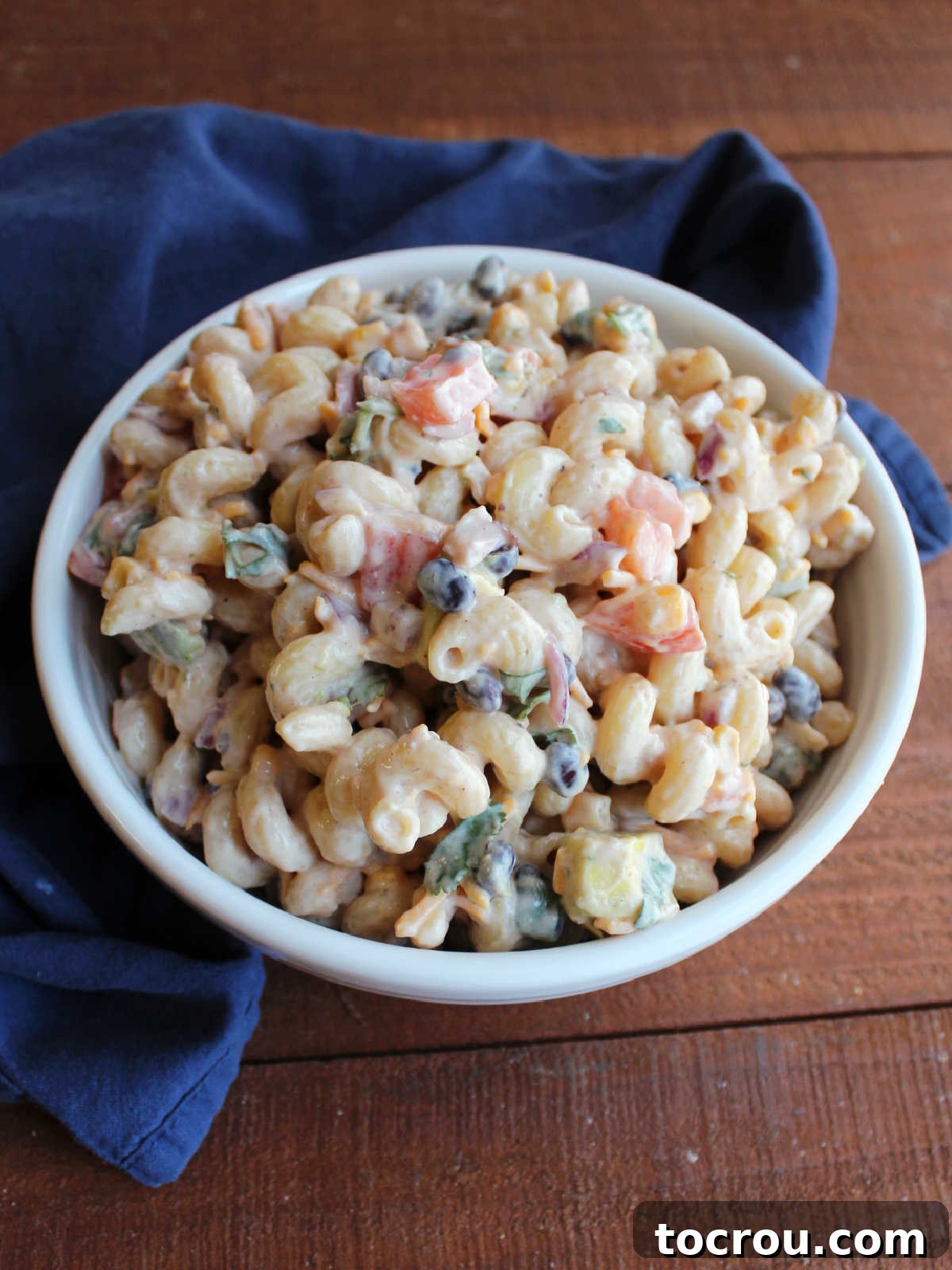 This pasta salad has it all, BBQ, ranch, tomatoes, avocados, corn and more! It's perfect for picnics, BBQs, potlucks and more! Serving bowl filled with creamy bbq ranch pasta salad loaded with corn, black beans, veggies and cheese.