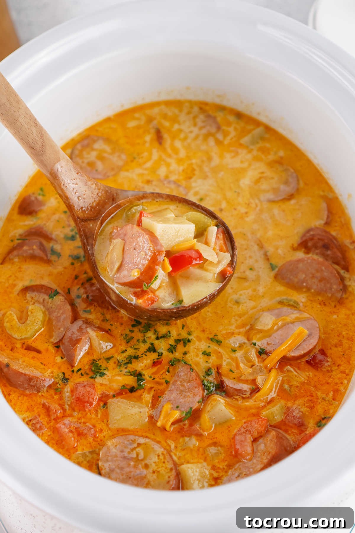 Ladle scooping a serving of Cajun potato soup out of the crockpot it was cooked in. 