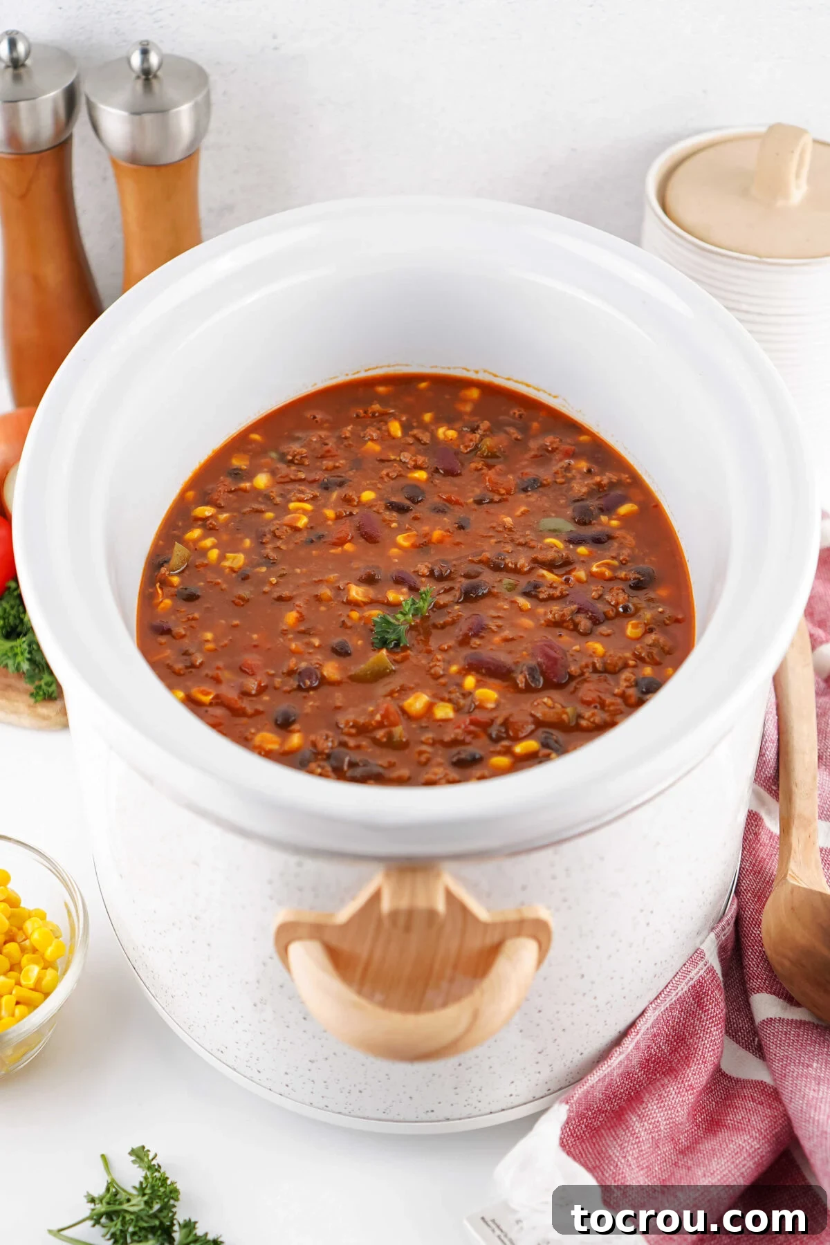 A slow cooker brimming with rich Cowboy Soup, showcasing browned ground beef and an assortment of vegetables in a savory BBQ and tomato sauce base.