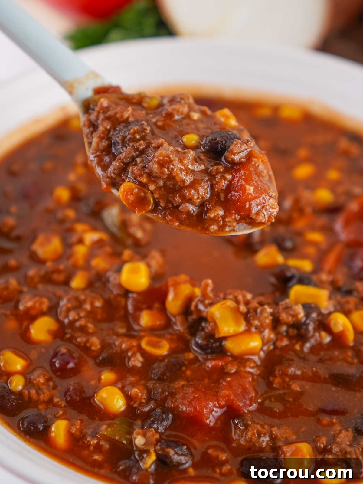 A spoonful of slow cooker Cowboy Soup, loaded with chunky ingredients, poised for a delicious bite.