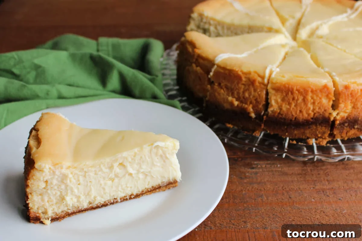 Irresistible Key Lime Cheesecake Slice A delectable slice of creamy Key Lime Cheesecake sits on a plate, with the rest of the whole cheesecake blurred in the background, ready to be enjoyed.