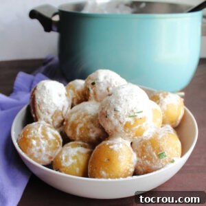 Bowl of new potatoes coated in sour cream and chives in front of pot.