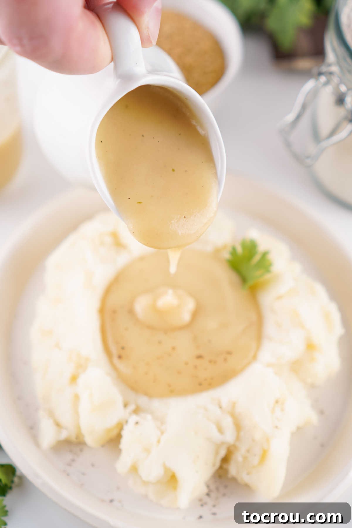 Delicious Homemade Brown Gravy Blend 4 Small pitcher pouring homemade beef gravy made from the mix over mashed potatoes.