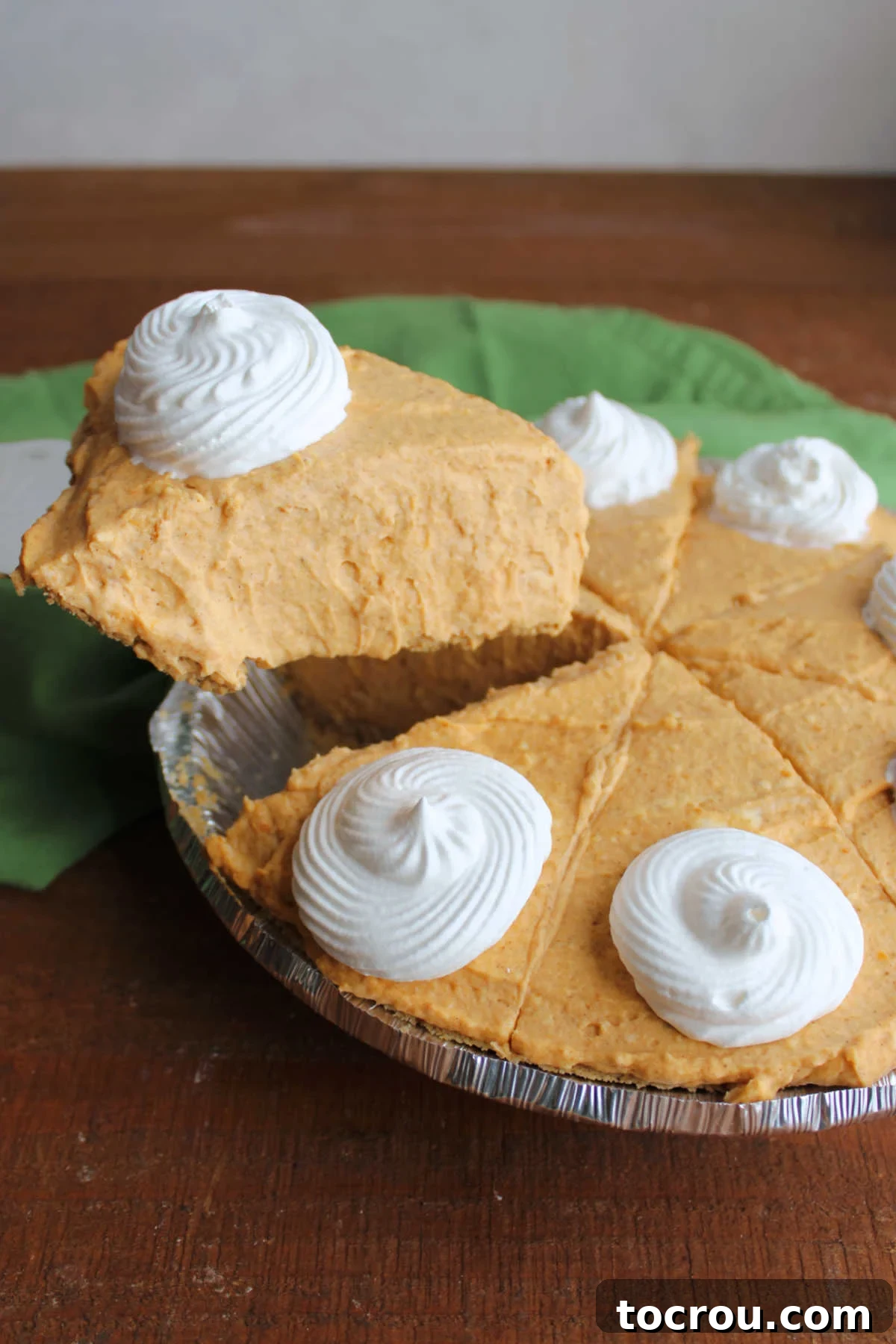 Effortless No-Bake Pumpkin Delight 3 Lifting a piece of no bake pumpkin pie out of the pie pan showing fluffy creamy texture of the pumpkin filling in a graham cracker crust.