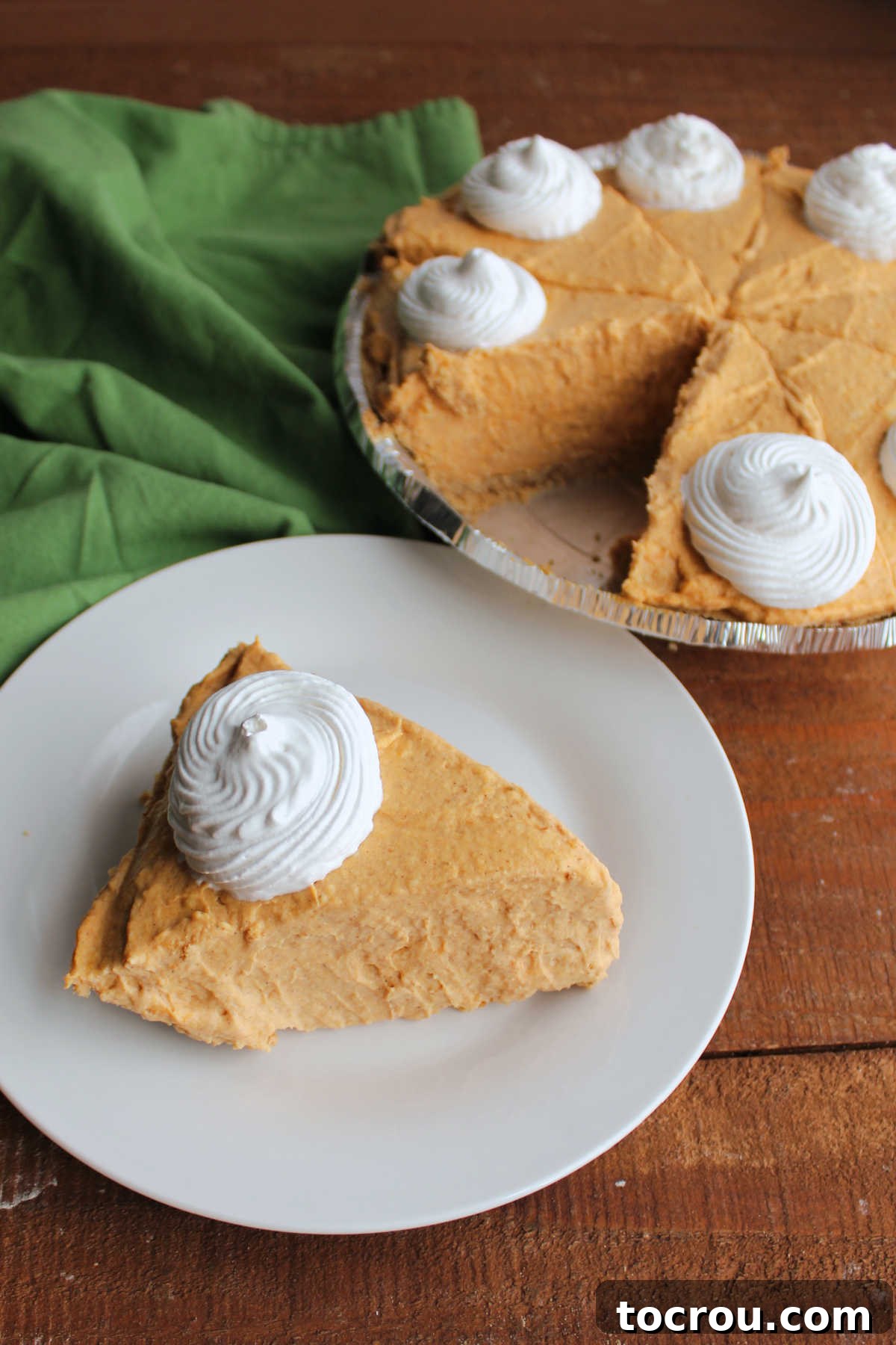 Effortless No-Bake Pumpkin Delight 4 Slice of creamy no bake pumpkin pie on plate next to the pie plate with the remaining pie.