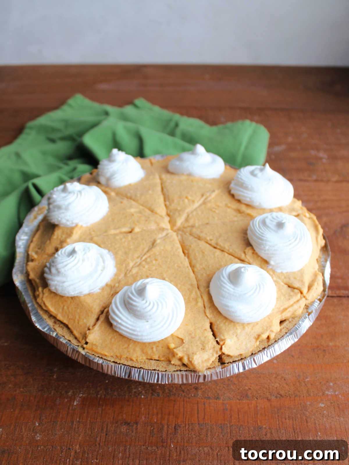 Effortless No-Bake Pumpkin Delight 6 Chilled no bake pumpkin pie cut into slices with swirls of whipped cream piped onto each piece.