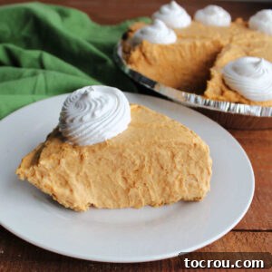 Slice of fluffy no bake pumpkin pie topped with swirl of whipped cream, ready to eat.