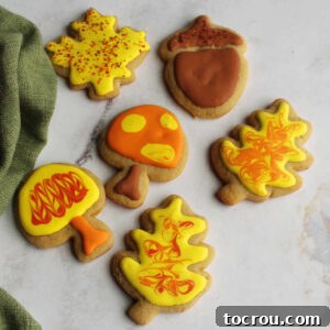 Cinnamon Brown Sugar Cookies Delicately frosted cinnamon brown sugar cookies, shaped into festive autumn leaves, mushrooms, and acorns, adorned with intricate royal icing designs.