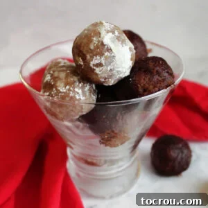 Pecan Bourbon Balls A sophisticated stemless martini glass filled with exquisite bourbon balls, some lightly dusted with powdered sugar and others with cocoa powder, offering a delightful adult treat.