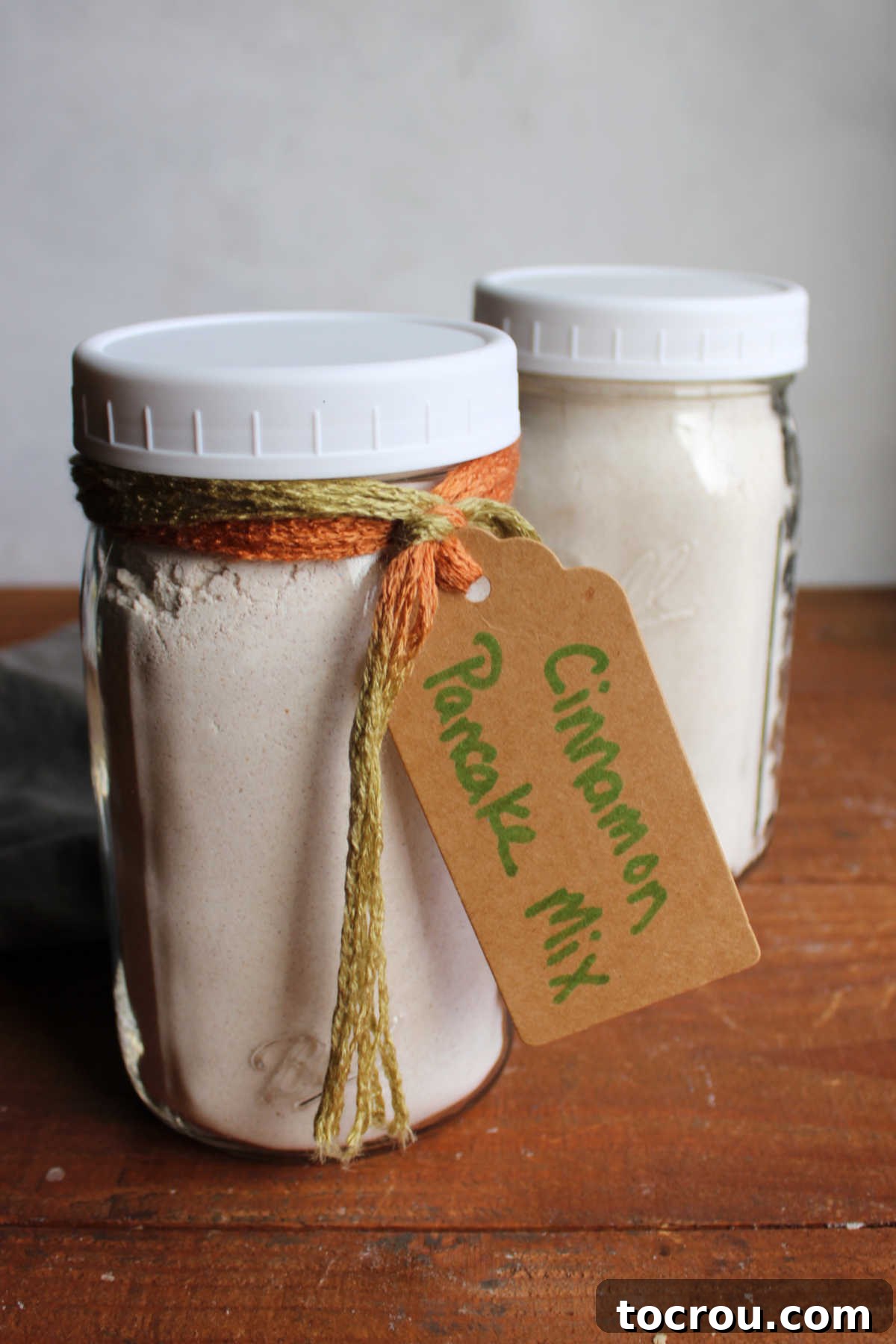 Cinnamon Pancake Mix Jars Two quart jars filled with homemade cinnamon pancake mix with a gift tag on one saying what is inside and how to make the pancakes.