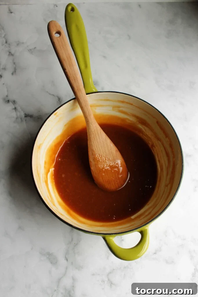 Enameled cast iron saucepan with homemade dulce de leche and a wooden spoon.