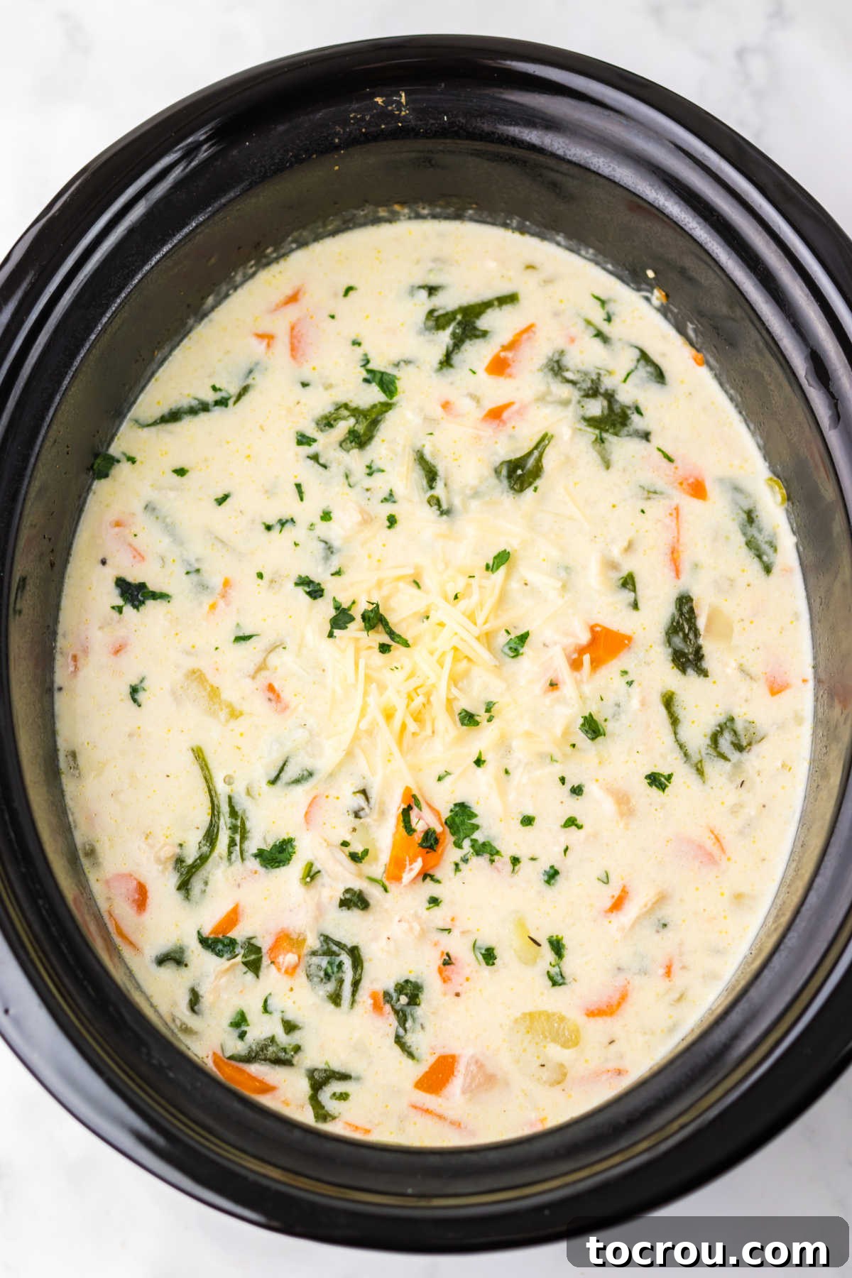 Ready-to-Serve Crockpot Chicken Gnocchi Soup A crockpot filled with steaming, creamy chicken gnocchi soup, highlighting the tender gnocchi, shredded chicken, vibrant spinach, and diced carrots and celery, ready for serving.
