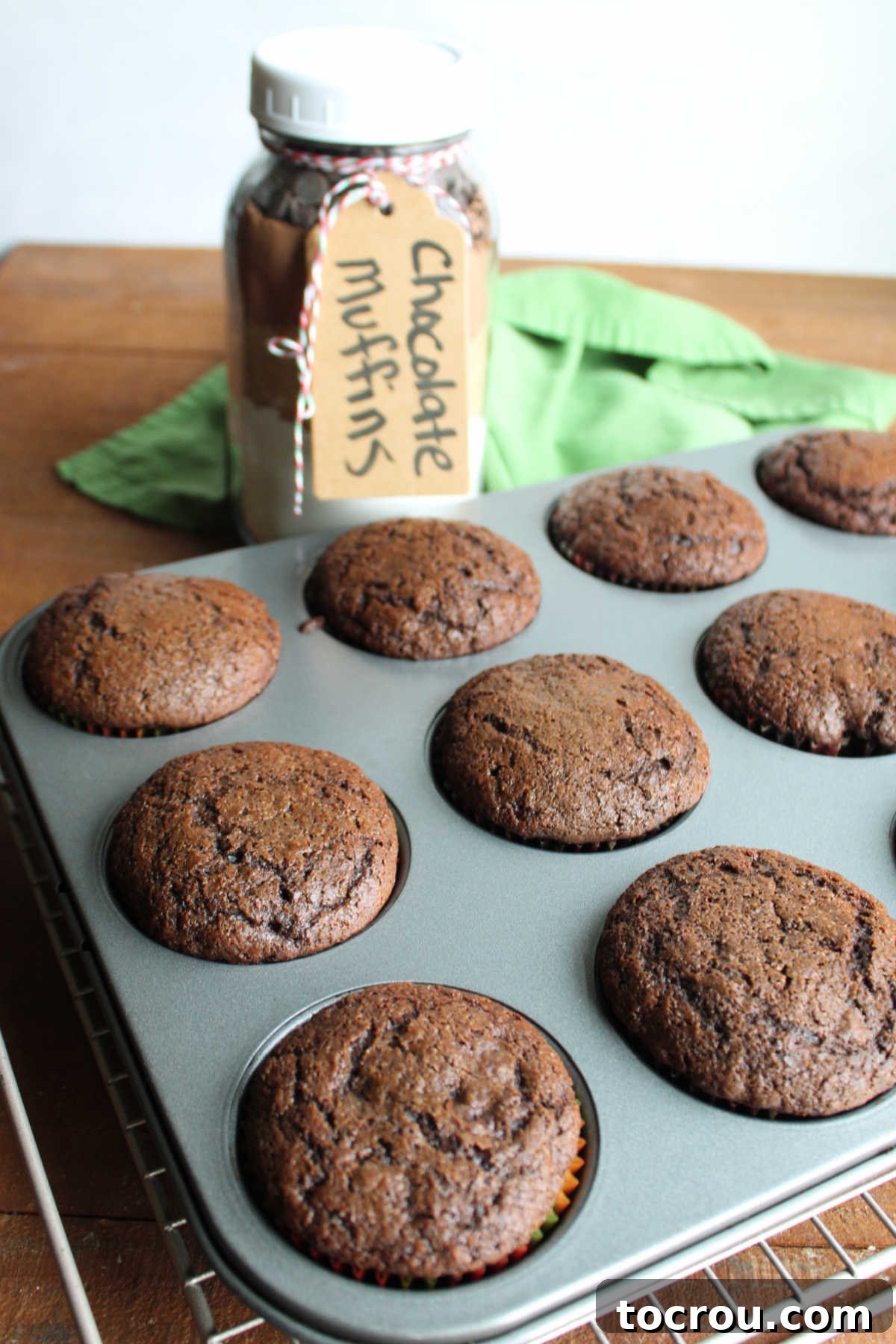 Muffin pan filled with freshly baked double chocolate muffins cooling on wire rack.