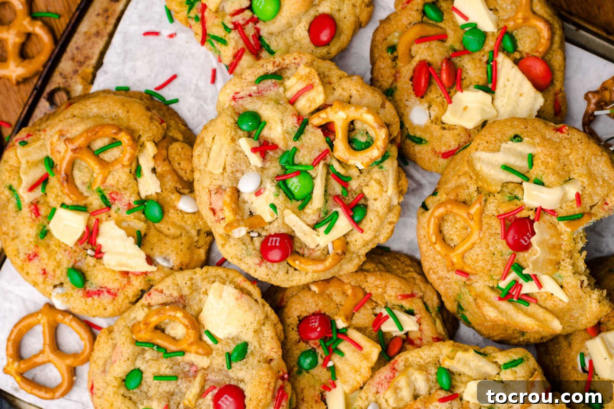 Baked Christmas junkyard cookies with large golden cookies filled with all sorts of goodies like pretzels, potato chips, sprinkles, white chocolate chunks, and M&M candies. 