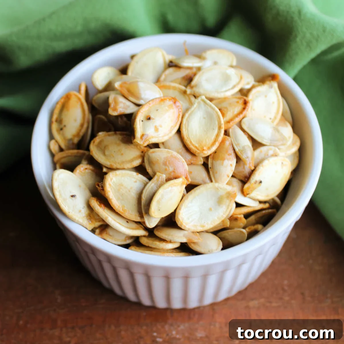 Crunchy Pumpkin Perfection 2 Small bowl filled with golden roasted pumpkin seeds with salt, pepper and garlic.