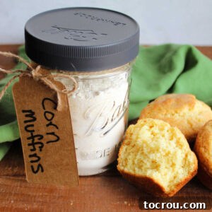 Pint jar with homemade corn muffin mix inside next to a half of a corn muffin showing the soft yellow interior.