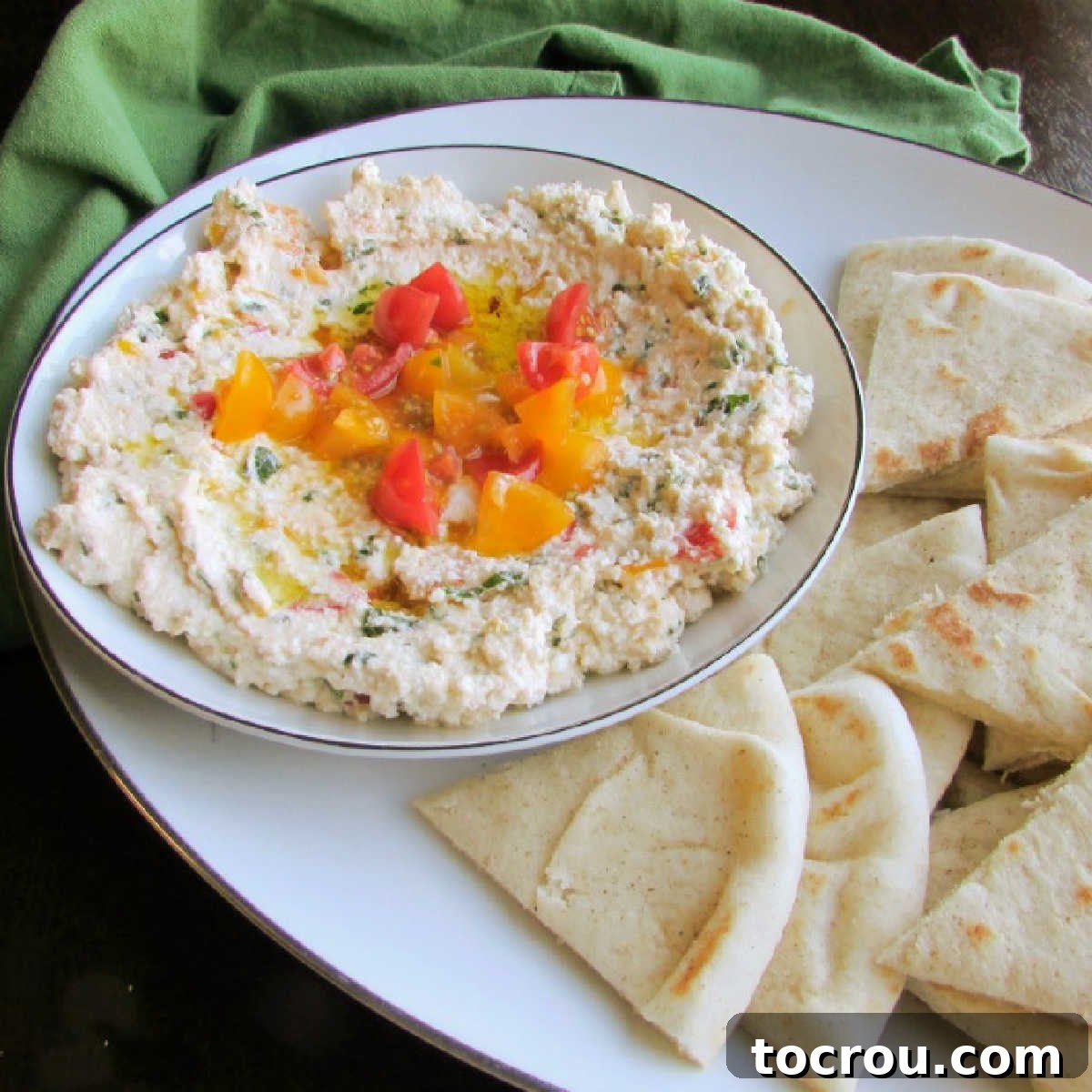 Egyptian Feta Spread with Pita Bowl of creamy Egyptian feta spread with vibrant herbs and diced tomatoes, served alongside warm pita bread wedges on a rustic platter.