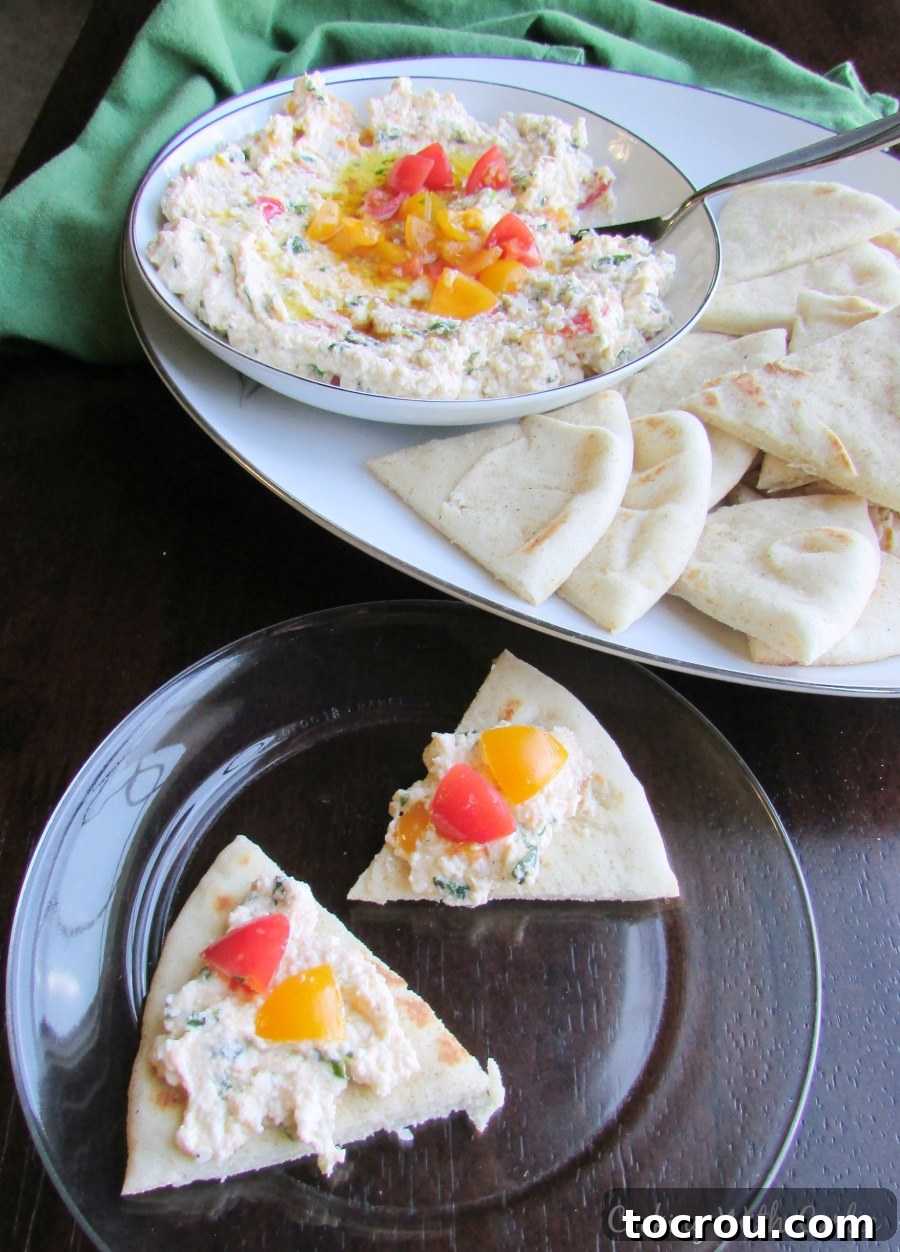 A perfect mix of fresh herbs, lemon juice, feta, tomatoes and extra virgin olive oil spread over pita. This would make a perfect starter for your next meal! Close-up of fluffy feta cheese spread on golden pita wedges, ready for a delicious bite.