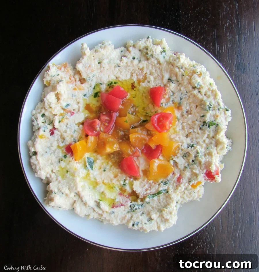 A perfect mix of fresh herbs, lemon juice, feta, tomatoes and extra virgin olive oil spread over pita. This would make a perfect starter for your next meal! Small rustic bowl of creamy feta mixed with vibrant green herbs and diced red tomatoes, ready to be served.