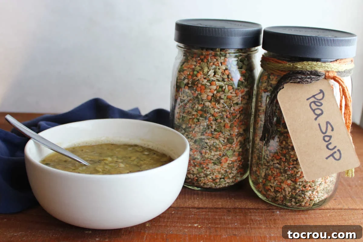 Homemade Pea Soup Mix and Cooked Soup A comforting bowl of split pea soup, rich and thick, served alongside beautifully layered jars of homemade pea soup mix containing split peas, lentils, pearled barley, dried vegetables, and seasonings. The scene evokes warmth and homemade goodness.
