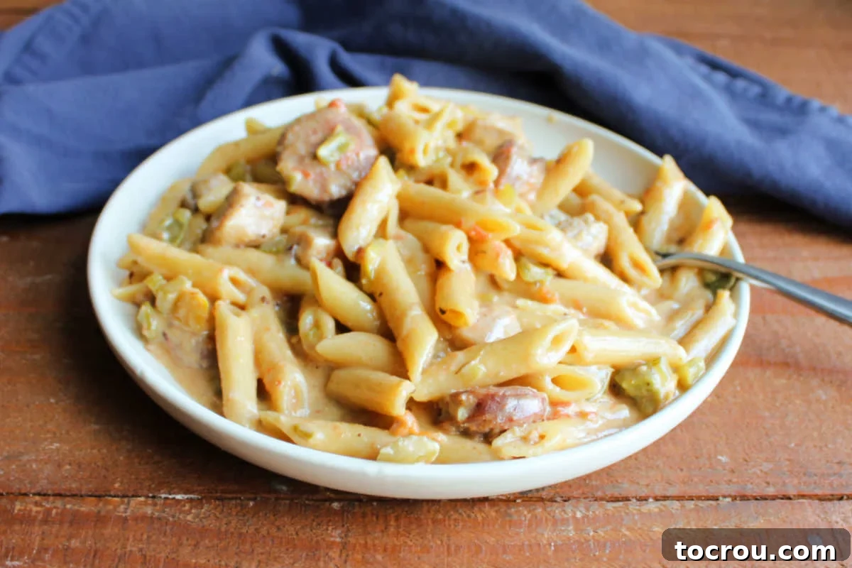 Plate with a generous serving of pastalaya, showcasing penne pasta in a creamy, flavorful sauce with visible pieces of chicken, sausage, bell peppers, and onions.