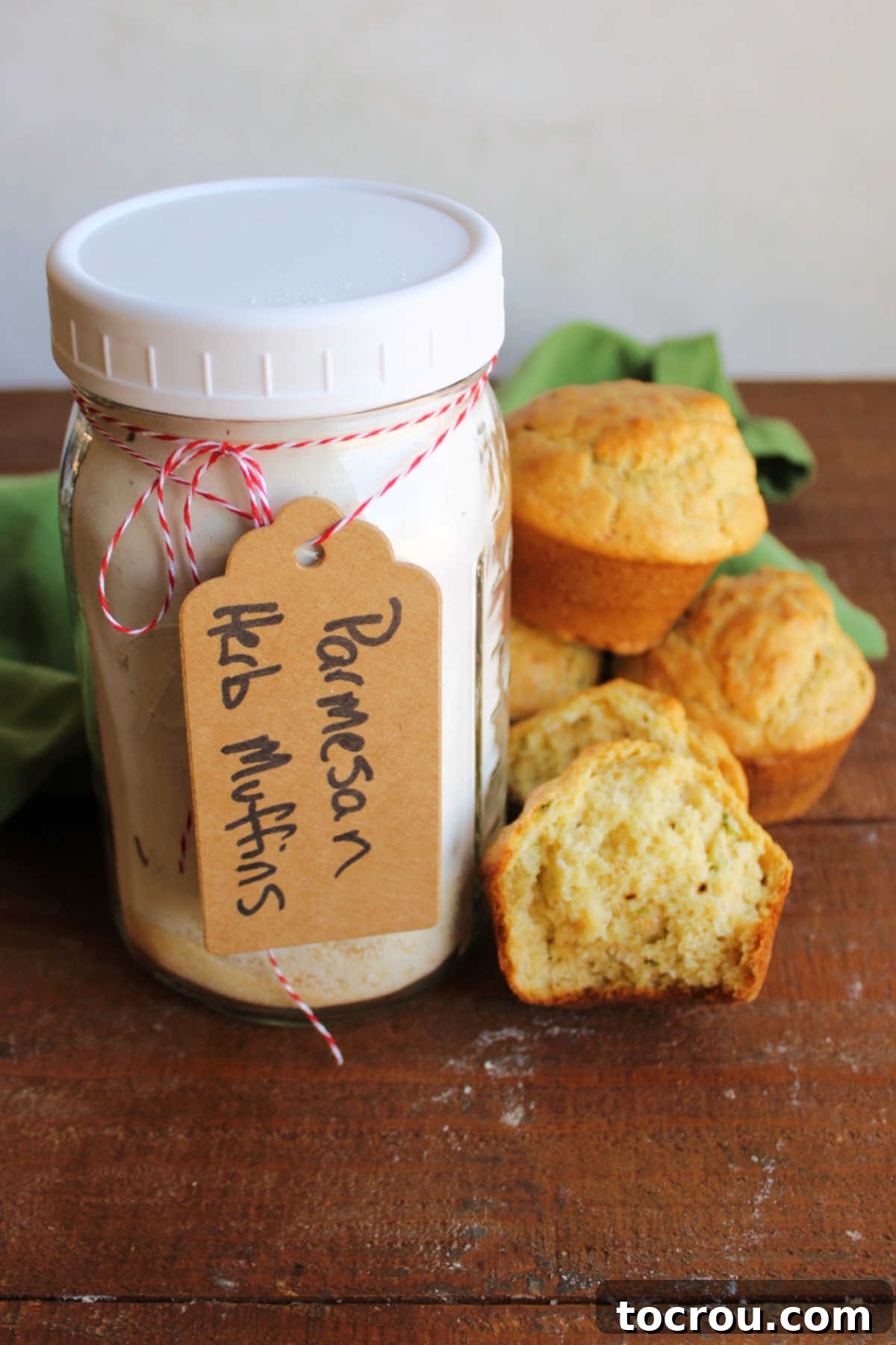 Jar of savory muffin mix next to a stack of muffins with one torn in half showing the soft interior.