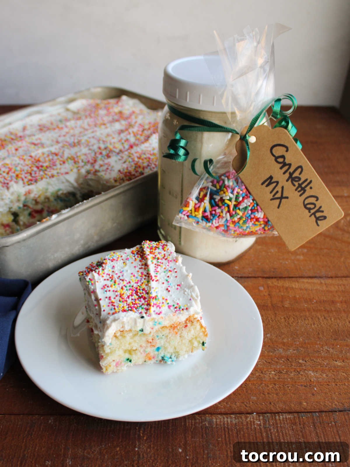 Confetti Cake with Homemade Frosting Piece of confetti cake with homemade condensed milk frosting and sprinkles on top next to a jar of homemade cake mix with sprinkles.