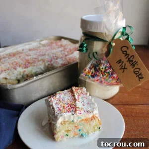 Piece of funfetti cake with fluffy frosting and more sprinkles on top next to a quart jar with homemade confetti cake mix inside.