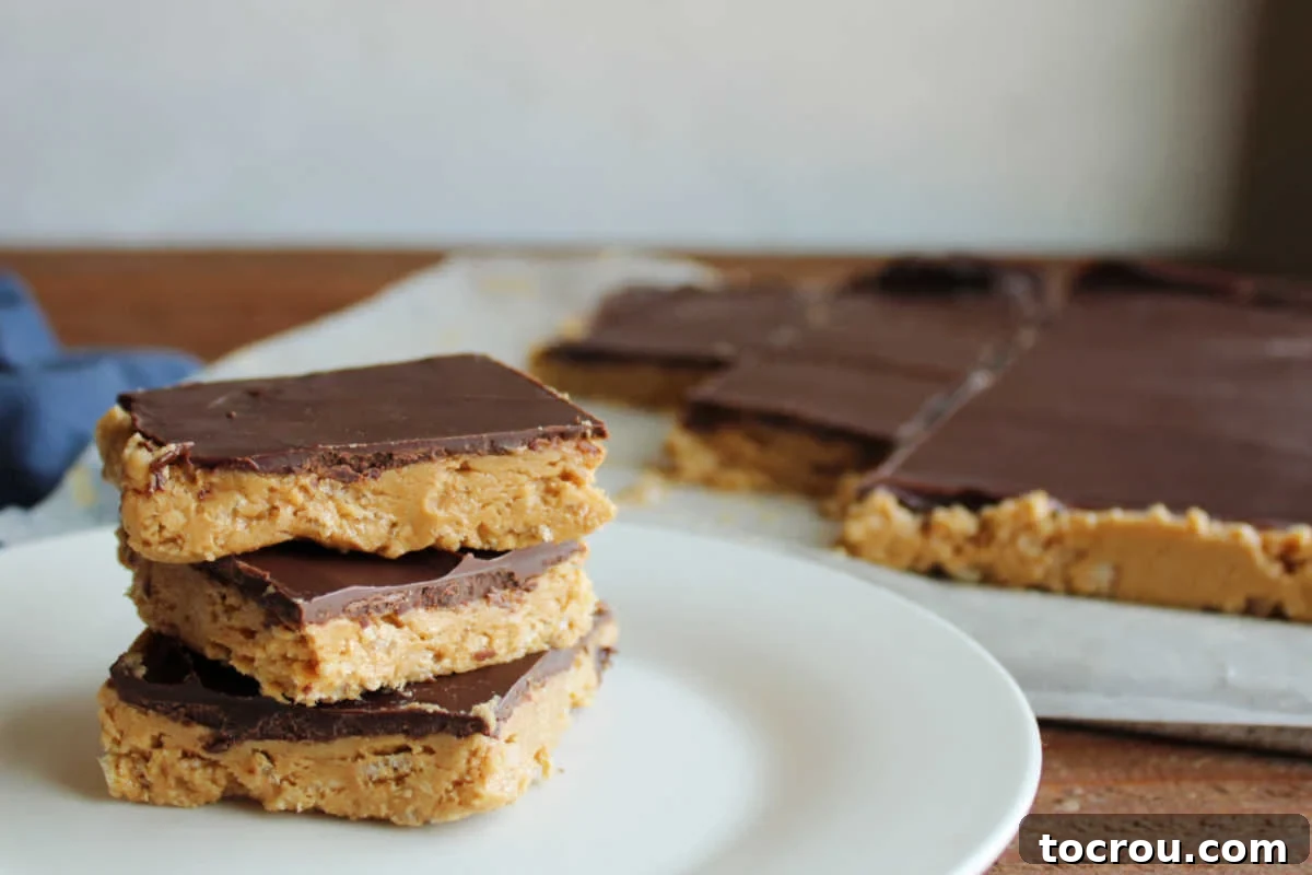Crispy Peanut Butter Chocolate Squares 2 Stack of peanut butter and chocolate buckeye bars with rice krispies next to a cutting board with the remaining bars on it.
