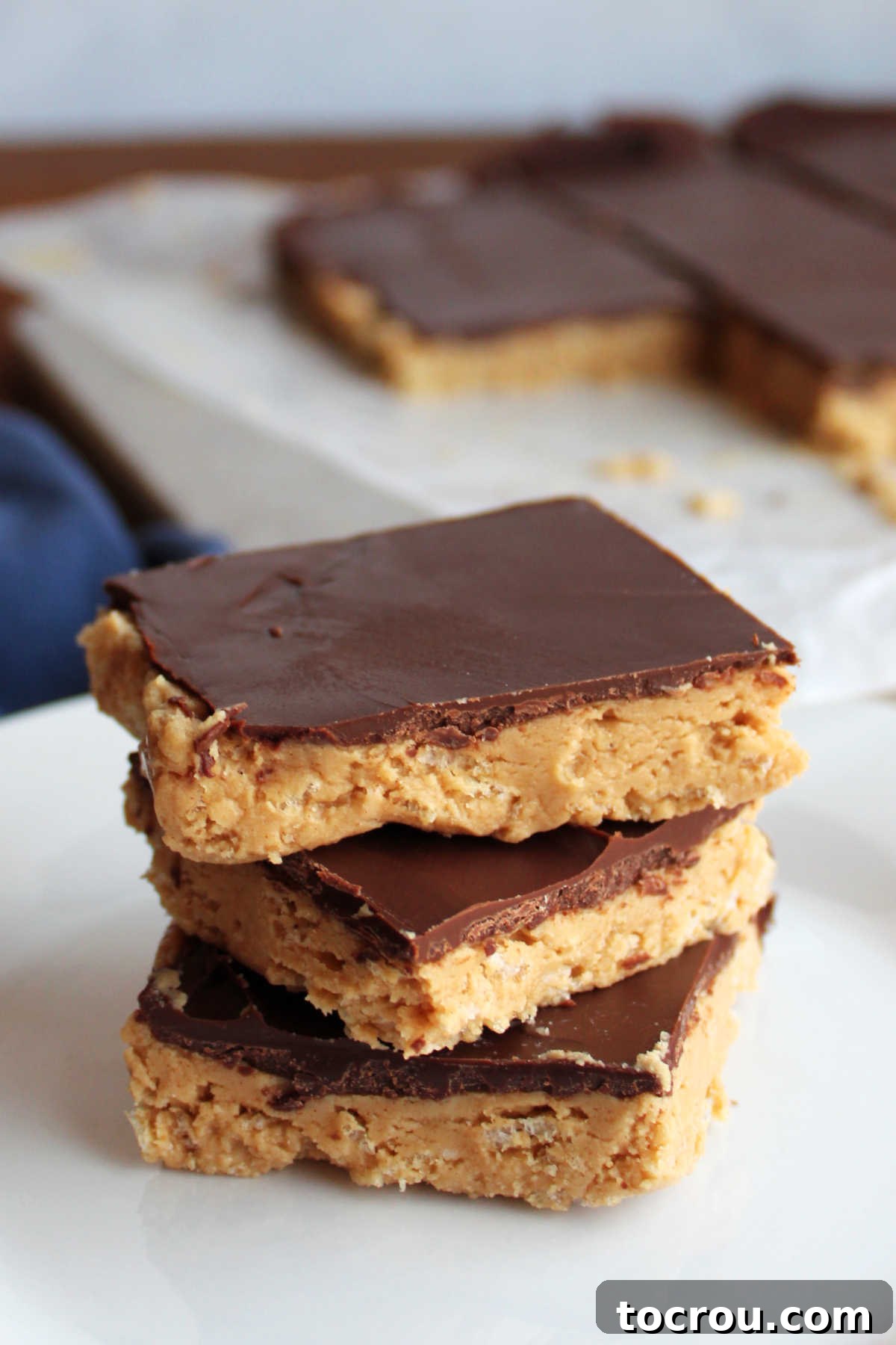 Crispy Peanut Butter Chocolate Squares 4 Stack of crunchy peanut butter bars with Rice Krispies in the peanut butter layer and a chocolate shell on top.