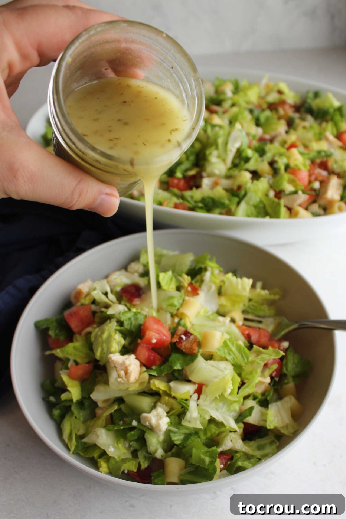 Chicago Chopped Salad Classic 9 Pouring salad dressing over small bowl of chopped salad.
