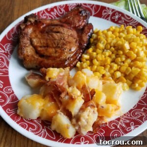 plate of BBQ pork chops, corn and potatoes with cheese and bacon.