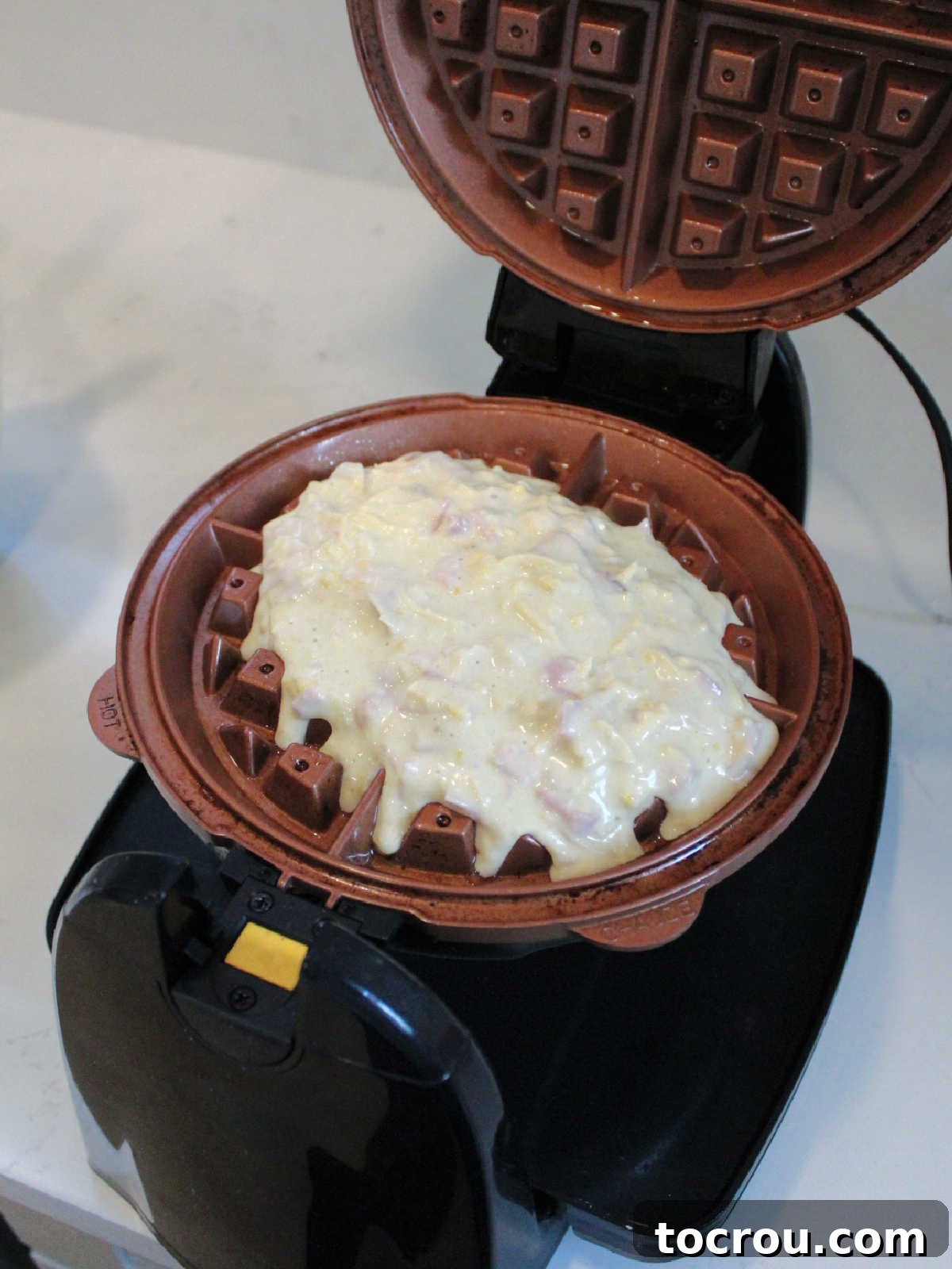 Waffled Croque Madame 4 Waffle batter with ham and cheese inside of waffle iron, ready to be cooked to golden perfection.