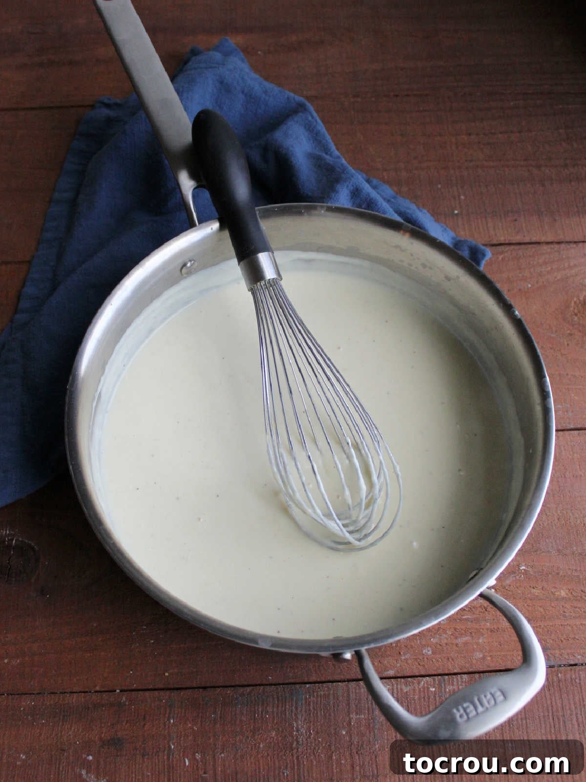 Waffled Croque Madame 5 Creamy bechamel sauce with a touch of Dijon mustard in a pan with the whisk, ready to go on the waffles.