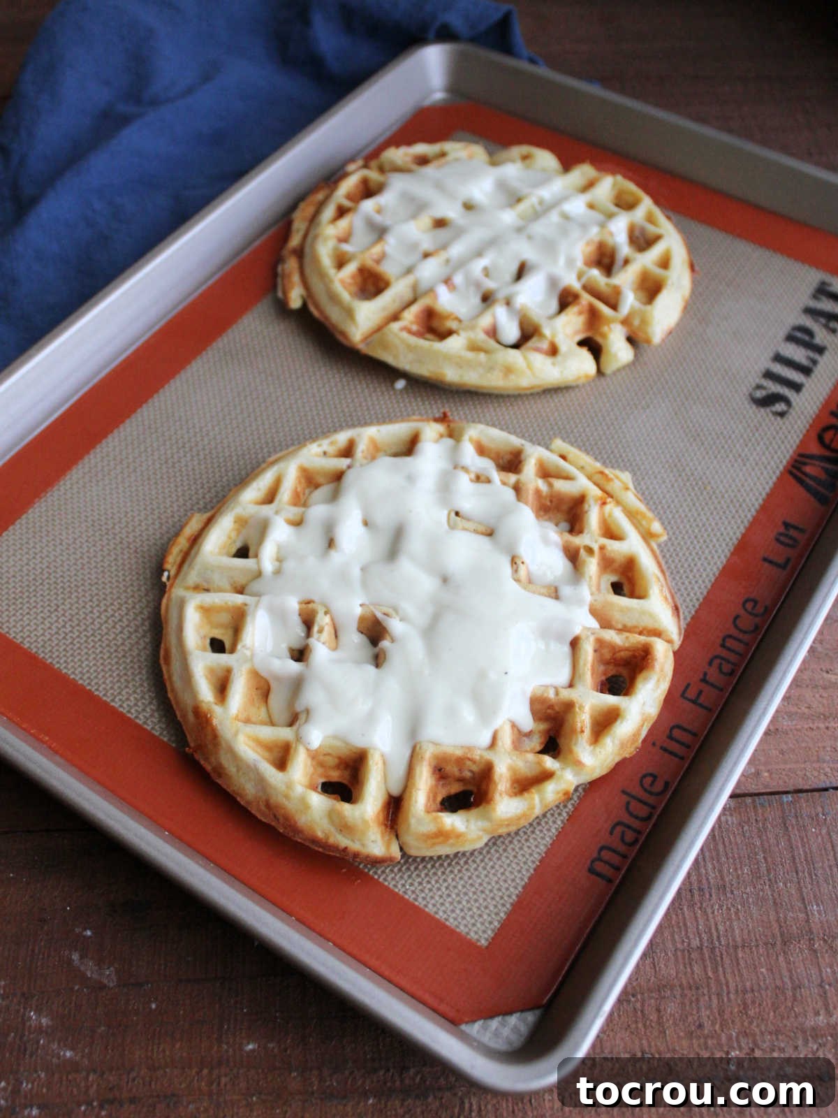 Waffled Croque Madame 7 Bechamel drizzled over waffles on a baking sheet, preparing for cheese and ham.