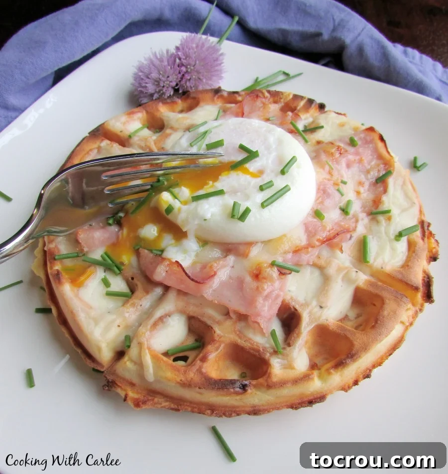 This is sure to become a brunch favorite. A ham and cheddar waffle is topped with creamy Dijon bechamel. More ham and cheese and a perfectly poached egg seal the deal for a fun brunch style twist on the classic French sandwich. Fork breaking into runny poached egg yolk on top of waffle topped with bechamel, ham and cheese.