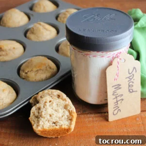 A glass jar of homemade spiced muffin mix sits beside a muffin tin filled with perfectly baked spiced muffins, inviting you to enjoy a warm, comforting treat.