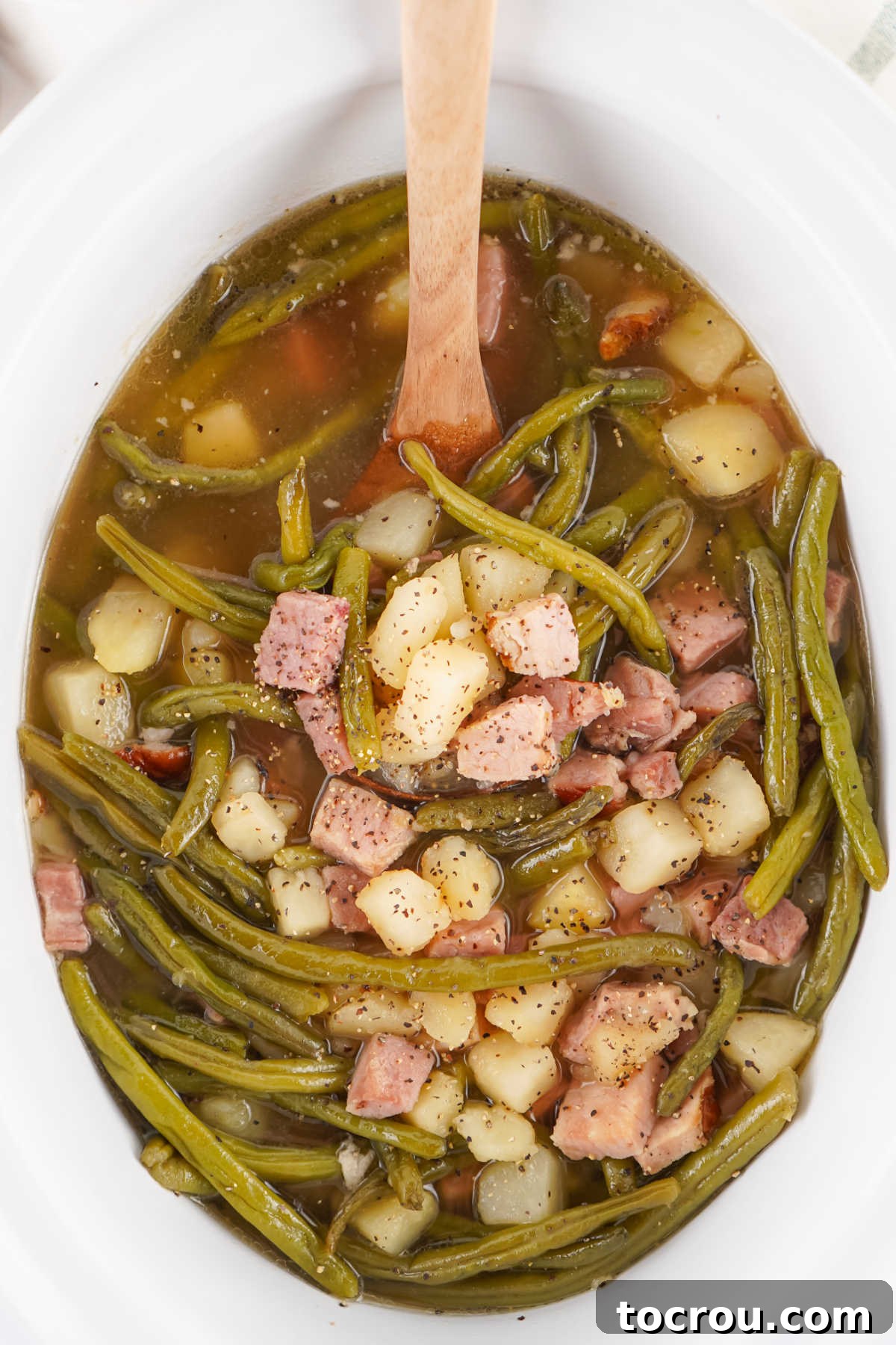 Southern Comfort Slow Cooker Ham Green Beans and Potatoes 3 Crockpot filled with green beans with chunks of ham and potatoes in a well seasoned broth.