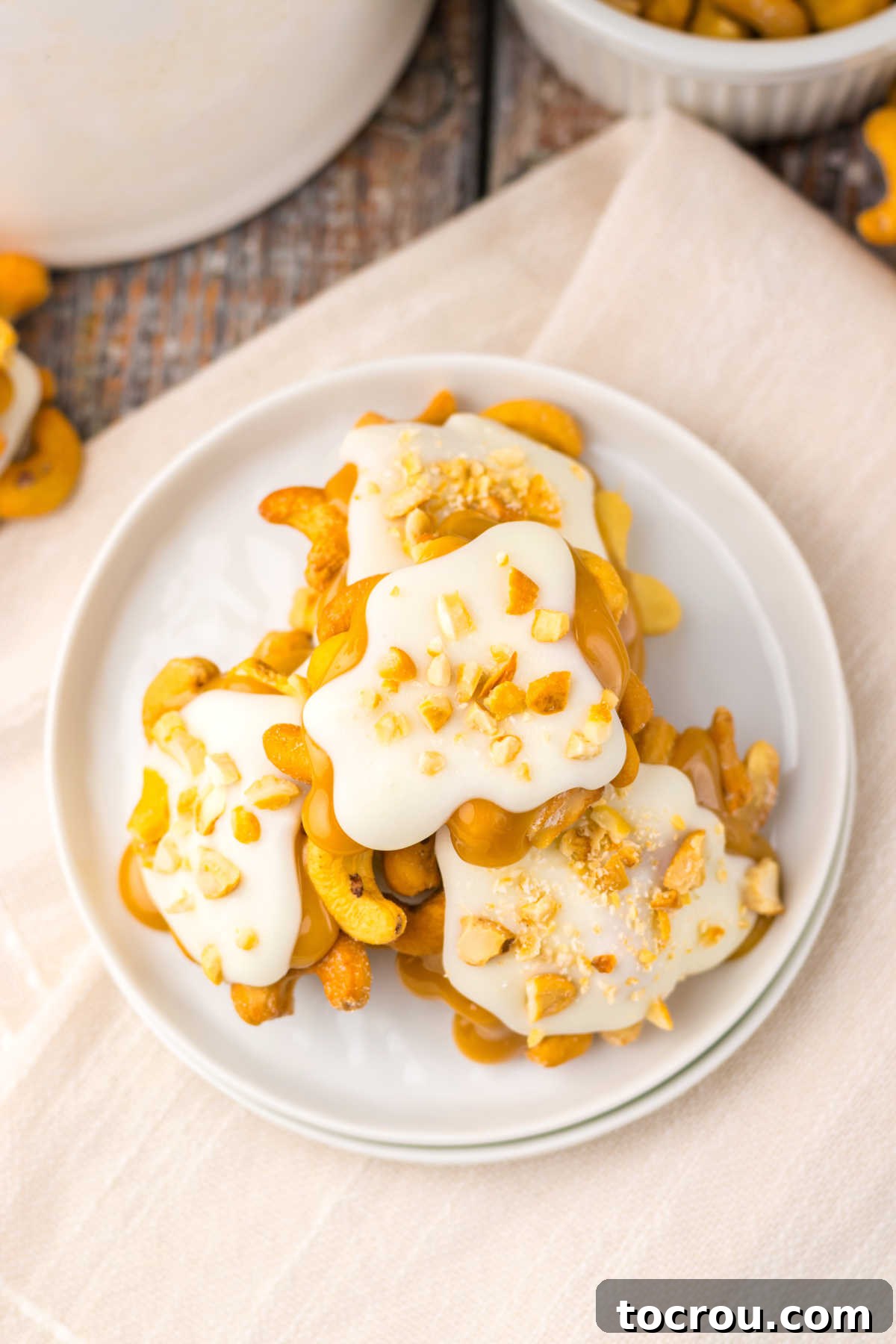 Looking down on a plate of homemade white chocolate caramel cashew clusters with edges caramel and nuts visible under white chocolate topping. 
